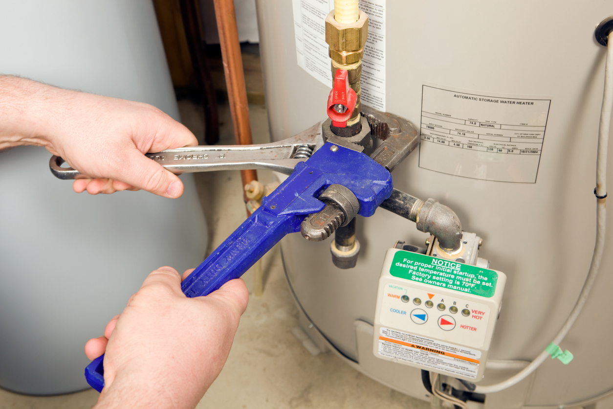 Plumber tightening a nut in water heater system with adjustable wrench